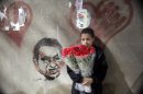 An Egyptian flowers vendor stands in front of graffiti depicting president Hosni Mubarak as he waits for a customer in Cairo, Egypt, Thursday, May 31, 2012, two days before Mubarak is to hear the verdict on charges of corruption and complicity in killing protesters during last year's uprising. (AP Photo/Amr Nabil)