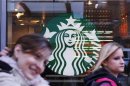 Pedestrians walk past the new Starbucks logo on a store in Times Square in New York