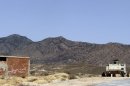 In this photo taken on June 25, 2013, a Tunisian armored personnel carrier patrols near the Jebel Chaambi mountain. Writing on building at left reads: "For Sale". Gunmen ambushed a Tunisian army patrol Monday July 29, 2013 in a mountainous border region known as a militant stronghold, killing at least eight soldiers, the presidential spokesman said. (AP Photo/Paul Schemm)