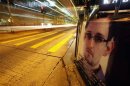 A bus passes by a poster of Edward Snowden, a former contractor at the NSA displayed by his supporters at Hong Kong's financial Central district