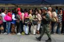 A Venezuelan soldier patrols as people queue outside Venezuela's Central Bank (BCV) in Caracas in an attempt to change 100 Bolivar notes, on December 17, 2016