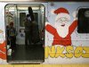 A man rides the subway shuttle that is decorated with a Santa Claus from Grand Central Terminal in New York
