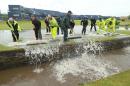 Ground staff sweep flood water into the Swilcan Burn after heavy rain delayed the start of the second round of the British Open Golf Championship at the Old Course, St. Andrews, Scotland, Friday, July 17, 2015. (AP Photo/Peter Morrison)