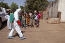 In this photo taken Friday, Nov. 14, 2014, a health worker sprays disinfectant near a mosque, after the body of a man suspected of dying from the Ebola virus was washed inside before being berried in Bamako, Mali. It all started with a sick nurse, whose positive test results for Ebola came only after death. In a busy clinic that treats Bamako's elite as well as wounded U.N. peacekeepers, who was the patient who had transmitted the virus? Soon hospital officials were taking a second look at the case of a 70-year-old man brought to the capital late at night from Guinea suffering from kidney failure. On Friday, Malian health authorities went to disinfect the mosque where the 70-year-old's body was prepared for burial - nearly three weeks ago. Already some are criticizing the government for being too slow to react when health authorities had announced his death as a suspected Ebola case earlier in the week. (AP Photo/Baba Ahmed)