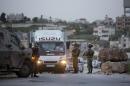Israeli soldiers check Palestinians at a checkpoint on the road to the village of Hajja near the West Bank city of Nablus, Wednesday, March 9, 2016. Israeli army imposed the blockade after a Palestinian from the village killed an American tourist and wounded nearly a dozen people in the city of Jaffa on Tuesday. (AP Photo/Majdi Mohammed)