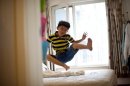 Zhang Hongwu enjoys one of the benefits of home schooling -- jumping on his parents' bed