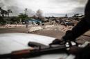 Smoke rises from a barricade as Gabonese police officers patrol from a pick up in Libreville on September 2, 2016