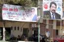 People sit at a coffee shop under election banners for parliamentary candidates in the Imbaba district of Giza, Egypt