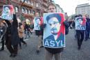 Protestors hold up placards featuring a picture of former NSA contractor Edward Snowden and with the world Asylum on it during a march against the spying methods of the US in Hamburg, northern Germany on December 28, 2013