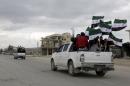 Protesters carry Free Syrian Army flags while riding pick-up trucks during an anti-government protest in the town of Marat Numan in Idlib province, Syria