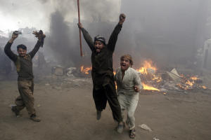 Pakistani men, part of an angry mob, react after burning …