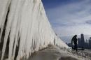 Man walks beside frozen wall on a beach in Chicago
