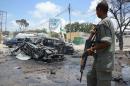 An armed man stands guard at the scene of two explosions in Mogadishu on September 7, 2013