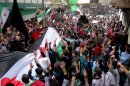 In this citizen journalism image provided by Aleppo Media Center AMC which has been authenticated based on its contents and other AP reporting, anti-Syrian regime protesters raise up their hands as they wave Syrian revolutionary flags during a protest to mark the second anniversary of the their uprising, in Aleppo, Syria, Friday March 15, 2013. The chief of Syria's main, western-backed rebel group marked the second anniversary of the start of the uprising against President Bashar Assad on Friday by pledging to fight until the "criminal" regime is gone. (AP Photo/Aleppo Media Center, AMC)
