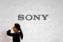 FILE PHOTO - A reception staff walks under a logo of Sony Corp at its headquarters in Tokyo