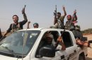 Unos combatientes rebeldes sirios festejan la toma del puesto de control en Anadan