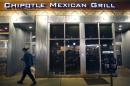 A man walks near a closed Chipotle restaurant on Monday, Dec. 7, 2015, in the Cleveland Circle neighborhood of Boston. Chipotle said late Monday that it closed the restaurant after several students at Boston College, including members of the men's basketball team, reported 