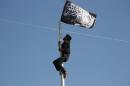 A member of al Qaeda's Nusra Front climbs a pole where a Nusra flag was raised at a central square in the northwestern city of Ariha, after a coalition of insurgent groups seized the area in Idlib provinc