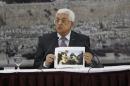 Palestinian President Mahmoud Abbas shows a picture of Palestinian minister Ziad Abu Ein as he is grabbed by an Israeli border policeman, during a meeting in Ramallah