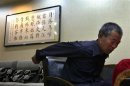 File picture showing Chen Guangfu, the eldest brother of blind Chinese activist Chen Guangcheng, showing how he had his hands tied behind a chair as he recounts the details of his torture after Chen Guangcheng's flight to the U.S., in Beijing