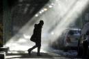 The sun illuminates windblown snow as a man walks under elevated train tracks, Wednesday, Jan. 22, 2014, in Philadelphia. A winter storm stretched from Kentucky to New England and hit hardest along the heavily populated Interstate 95 corridor between Philadelphia and Boston. (AP Photo/Matt Rourke)
