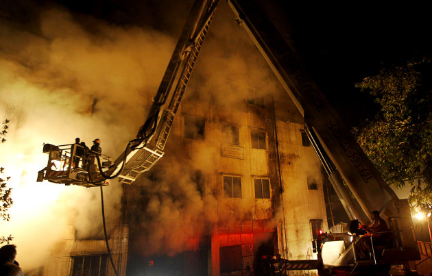 Firefighters battle a fire at a garment factory in the Savar neighborhood in Dhaka, Bangladesh, late Saturday, Nov. 24, 2012. At least 112 people were killed in a fire that raced through the multi-story garment factory just outside of Bangladesh's capital, an official said Sunday. (AP Photo/Hasan Raza)
