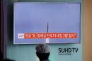 A passenger watches a TV screen broadcasting a news report on North Korea firing three ballistic missiles into the sea off its east coast, at a railway station in Seoul