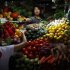A vegetable seller reaches to collect money from a customer in her stall at a market in central Beijing