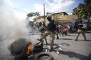 National police officers work to putout a burning barricade started by protesters during a march demanding the resignation of interim President Jocelerme Privert in Port-au-Prince, Haiti, Saturday, May 14, 2016. The Saturday demonstration of ex-President Michel Martelly's Tet Kale political faction reached a peak of a few thousand in downtown Port-au-Prince. Many chanted that interim Privert was illegally trying to hold onto power. (AP Photo/Dieu Nalio Chery)