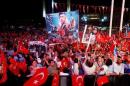 Supporters of Turkish President Erdogan wave national flags as they listen to him through a giant screen in Istanbul's Taksim Square