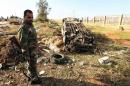A member of the Libyan security forces stands next to burnt-out vehicle on December 22, 2013 after a suicide bomber rammed an explosives-laden vehicle into a security checkpoint outside eastern Libya's restive city of Benghazi overnight
