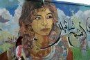 A girl walks past graffiti on a wall near Tahrir square in Cairo