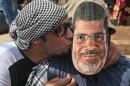 A supporter of Egypt's ousted President Mohammed Morsi, left, kisses his friend with Morsi's mask during a demonstration before the Friday prayer in Nasr City, Cairo, Egypt, Friday, July 12, 2013. Thousands of supporters of Egypt's Muslim Brotherhood group rallied in a Cairo city square, waving pictures of the ousted president and chanting anti-military slogans, deriding army chief who led Morsi's removal as 