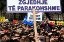 A protestor shouts slogans behind a placard reading "Early Elections" during a protest in front of the government building in Tirana on March 12, 2015, to demand the resignation of the parliament speaker