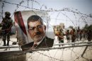 File photo of a portrait of deposed Egyptian President Mohamed Mursi seen on barbed wire outside the Republican Guard headquarters in Cairo