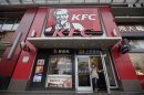 A woman walks out from a KFC restaurant as she speaks on her mobile phone in Wuhan