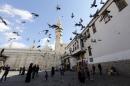 Syrians watch pigeons flying outside the Umayyad Mosque in the Syrian capital, Damascus, on November 10, 2015