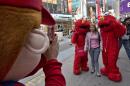 FILE - In this April 9, 2013 file photo, a Super Mario character, left, uses a woman's mobile phone camera to photograph her with a pair of Elmo characters in New York's Times Square. A New York City Council member is drafting legislation to regulate the costumed characters who roam Times Square. The bill being proposed by Councilman Dan Garodnick would require that the costumed performers be licensed and go through a background check. There have been a number of troublesome incidents involving costumed figures who try to make a living by charming tourists. (AP Photo/Richard Drew, File)