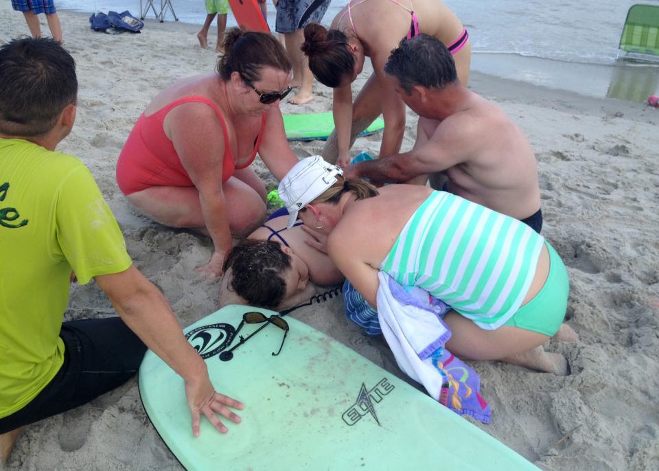People assist a teenage girl at the scene of a shark attack in Oak Island, N.C., Sunday, June 14, 2015. Mayor Betty Wallace of Oak Island, a seaside...