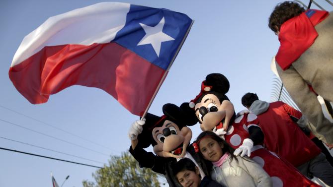 Fans take a picture with an official mascot of The Walt Disney Company before the Copa America semi-final soccer match between Chile and Peru at the National Stadium in Santiago, Chile