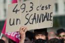 A man holds a placard reading, "49.3 is a scandal" during a demonstration on May 10, 2016 in Nantes, western France, to protest against the government's planned labour law reforms