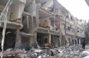 A man walks past buildings damaged after Syrian Air Force fighter jets loyal to Syria's President Bashar al-Assad fired missiles, in Erbeen
