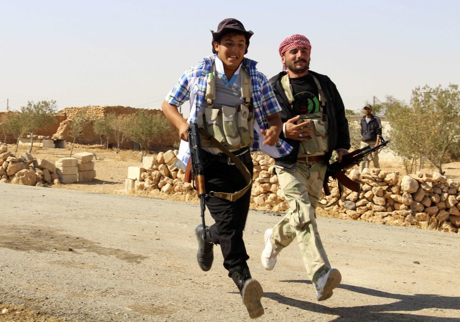 Free Syrian Army fighters carry their weapons as they run to take cover and to avoid snipers loyal to Syria's President Bashar al-Assad in the eastern Hama countryside