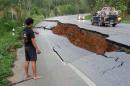 A man points a big crack on a damaged road following a strong earthquake in Phan district of Chiang Rai province, northern Thailand, Monday, May 5, 2014. A strong earthquake shook northern Thailand and Myanmar Monday evening, and some light damage was reported. (AP Photo)