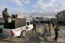 Forces loyal to Syria's president Bashar al-Assad stand by as an aid convoy of the Syrian Arab Red Crescent enters Wafideen Camp, which is controlled by Syrian government forces, to deliver aid into the rebel-held besieged Douma neighborhood of Damascus