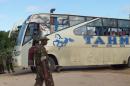 Police officers stand at the scene where a bus and a police vehicle were attacked by gunmen near the town of Witu, on Kenya's restive southeastern coast, on July 19, 2014