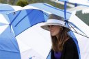 Hingis takes shelter under an umbrella as rain falls during the Tennis Hall of Fame induction ceremony in Newport