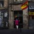 A woman stands next to Spanish flags as she waits to enter a building in central Madrid