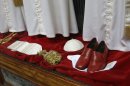 Papal shoes and a white skull cap are seen beneath three sets of papal outfits - small, medium and large sizes - which will be sent to the Vatican for the new pope, are displayed in the Gammarelli tailor shop window, in Rome, Monday, March 4, 2013. For over a half century the Gammarelli family has produced the pope robes in three different sizes that are delivered before the conclave meets, in order to fit the newly elected popes. (AP Photo/Andrew Medichini)