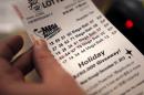 A cashier holds a Mega Millions lottery ticket at a convenience store in Lisbon, Maine, Tuesday, Dec. 17, 2013. With tickets selling well, the jackpot for tonight's drawing is now at an estimated $636 million, the second-biggest lottery prize in U.S. history. (AP Photo/Robert F. Bukaty)